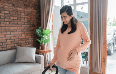 8d7e71c6 pregnant woman cleaning floor with vacuum cleaner 1